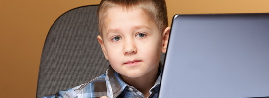 Computer addiction child boy with laptop computer brown background