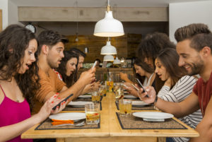 Group of friends at a restaurant with all people on the table occupied with cellphones