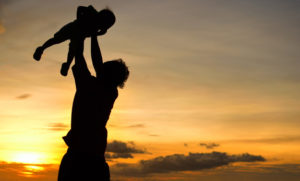 silhouette of daddy and small girl on the beach at dusk.